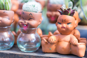 Potted cactus in the garden. The statue of a child showing emotion.