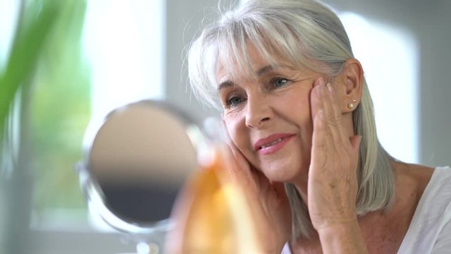 Portrait of senior woman applying anti-aging cream