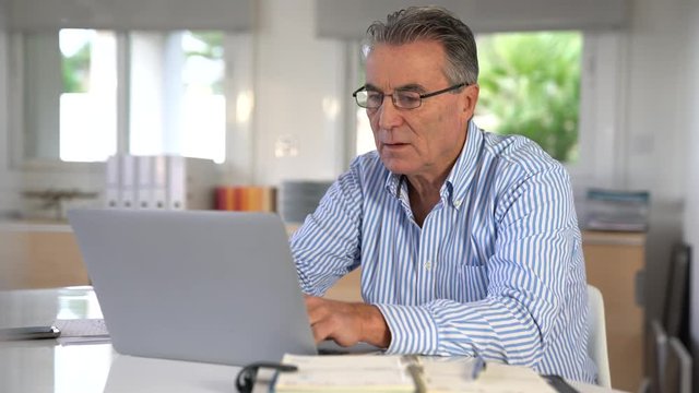 Senior man in office working on laptop computer