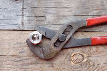 pliers and nut wood background