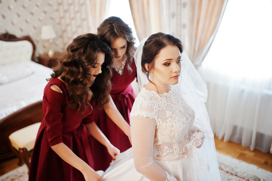 Two young and gorgeous bridesmaids on red dress wear bride on he