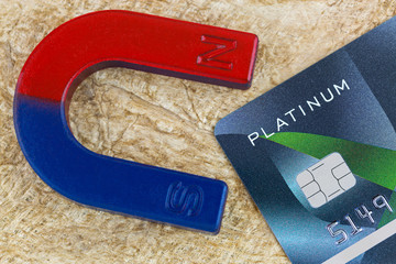 Closeup of magnet pulling platinum credit card on fiber paper background