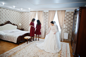 Two young and gorgeous bridesmaids on red dress wear bride on he