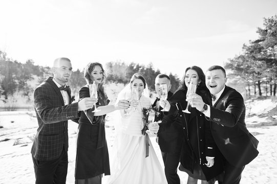 Best man with bridesmaids and newlyweds drinking champagne on fr