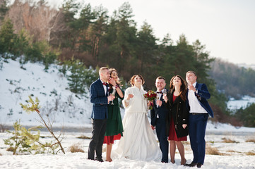 Best man with bridesmaids and newlyweds drinking champagne on fr