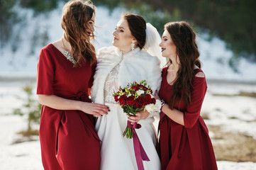 Pretty bridesmaids on red dresses with bride on sunny winter wed