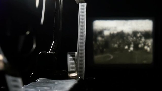 A moving retro film reel with strip in the black background. Closeup