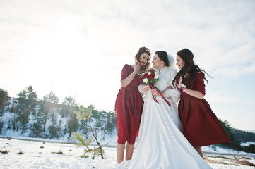Pretty bridesmaids on red dresses with bride on sunny winter wed