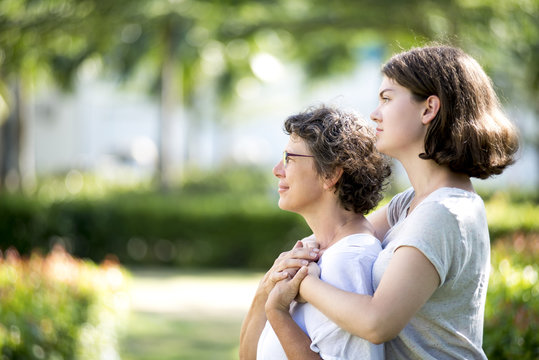 Serious Mother And Daughter Embracing Outdoors