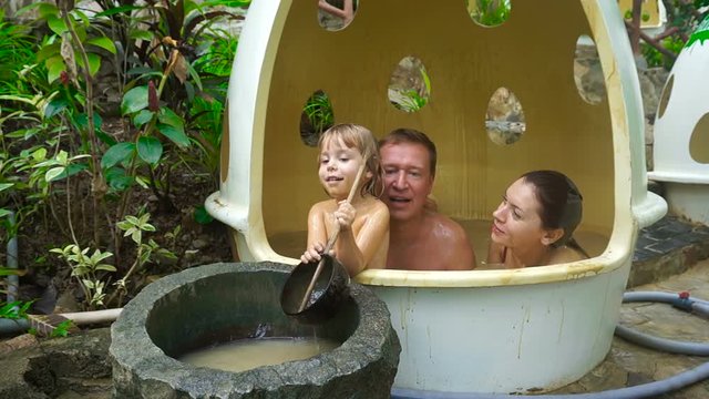 Father, mother and three or four year old child swimming in the mud bath.