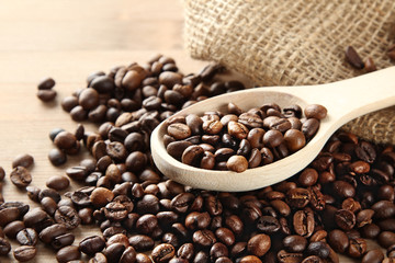 Handful of roasted coffee on a wooden table with a spoon.