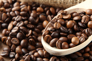 Handful of roasted coffee on a wooden table with a spoon.