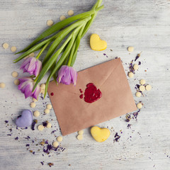 Envelope with wax seal and tulips on wooden background.