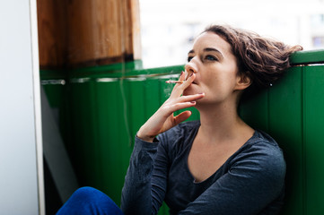 curly girl smokes on the balcony