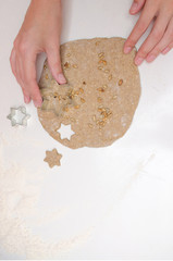 Female hands cut the cookies-stars from the rye dough with sunflower seeds on white table