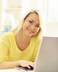 Happy blonde girl with notebook at home. Online shopping, laptop