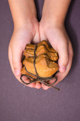 Child's hands hold homemade cookies stack tied with brown rope