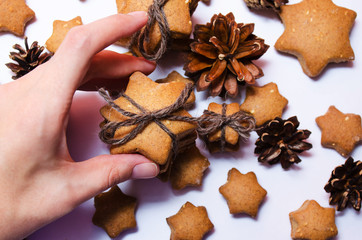female hand holding homemade rye cookies star shaped stack tied with brown rope on white background