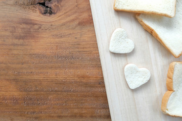Bread cut in the shape of hearts on wooden table