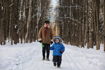 Fototapeta na wymiar Kid running in winter park and have fun with family