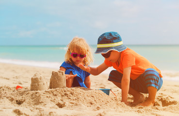 little boy and girl play with sand on summer beach