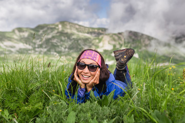 Naklejka premium Young woman relaxing on grass at high alpine meadows on hiking day