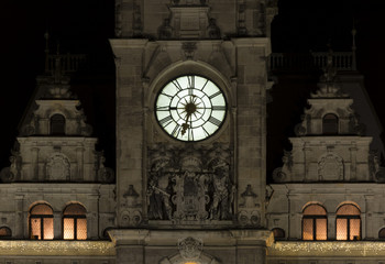 Night view of the illuminated clock on the tower of the town hall