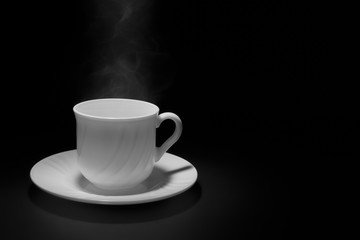 White cup and saucer with rising steam on a black background