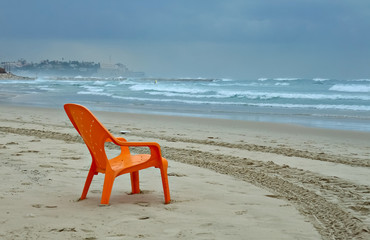 Tel-Aviv beach at winter storm, selective focus on a red resting chair