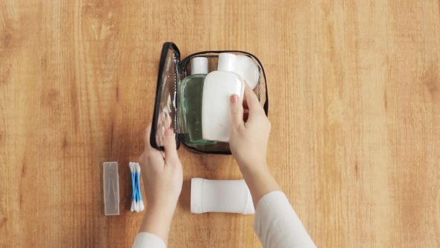 hands packing bag with cosmetics