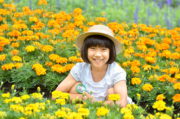 虫めがねで花を観察する女の子（麦わら帽子）