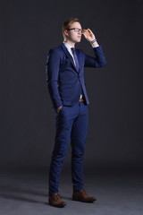 Young and confident business man. Businessman in suit over dark background. © Acronym