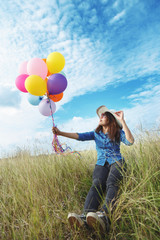 Beautiful woman at meadow with balloons in hand.