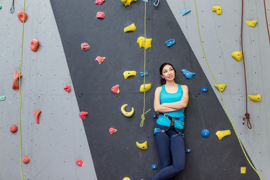 woman coach boulder stands near climbing wall and looking at the camera
