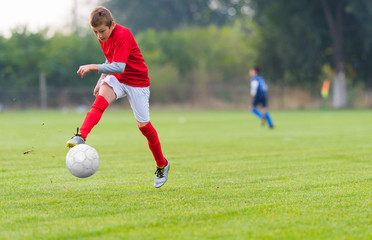 Obraz premium Boy kicking soccer ball
