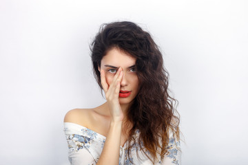 Beauty portrait of young adorable fresh looking brunette woman with healthy curly hair touching her face. Emotion and facial expression concept.