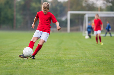 Obraz premium Boy kicking soccer ball