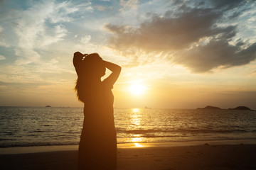 silhouette of woman pointing with finger in sky on the beach