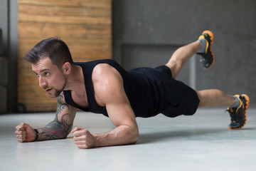 Young man fitness workout, raised leg plank
