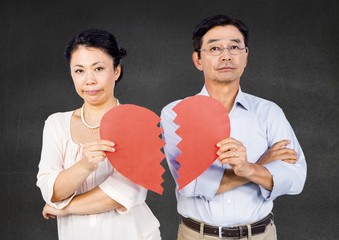 Displeased mature couple holding broken heart