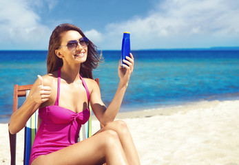 A young woman in a swimsuit adding suntan on the beach