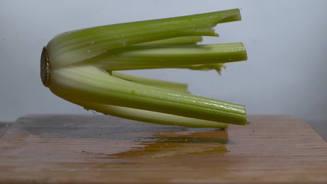 A celery stalk bounces in slow motion onto a cutting board