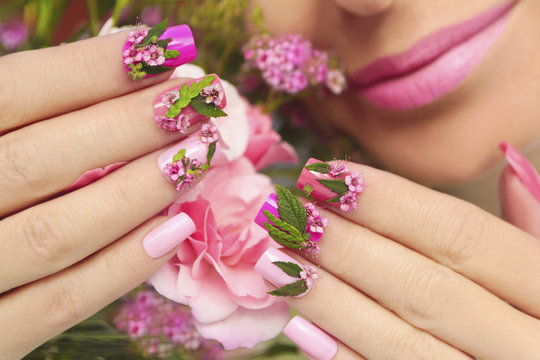Multicolored pastel manicure with a design of natural flowers on female hand close up.Summer nail design.