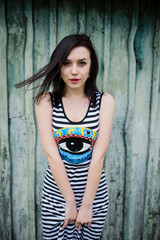 Brunette model girl at dress with stripes background cian wooden