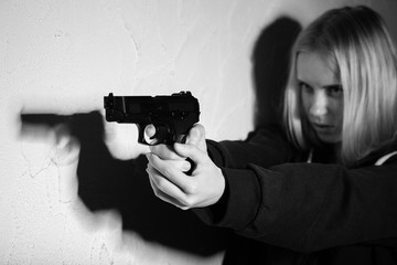 serious girl with gun aiming on wall background with copyspace