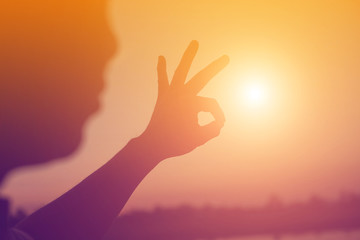 hands forming a heart shape with sunset silhouette