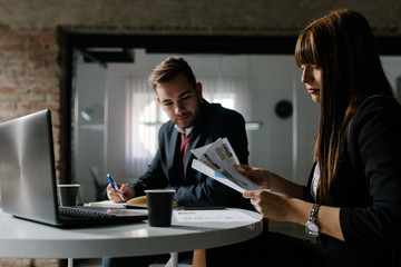 Two young people at the office sitting at the table and doing their work