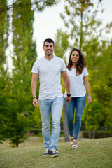 Happy young casual couple walking together in the park.