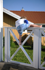 kleines kind in Kurzen Hosen klettert über einen Zaun