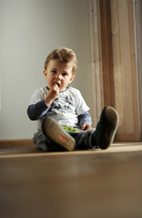 ein kleiner junge sitzt in der ecke auf dem Boden, und isst